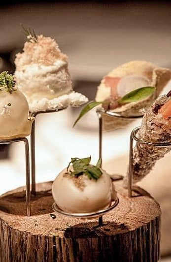 A tasting course served on a wooden block, garnished with herbs