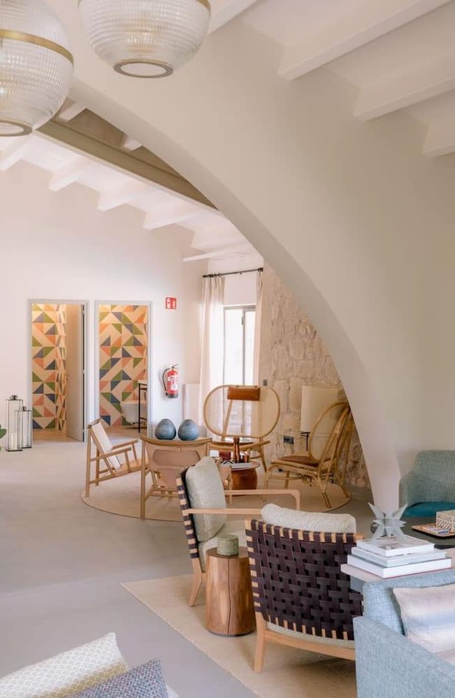 A bright, arched sitting room with woven chairs and tiled doorways