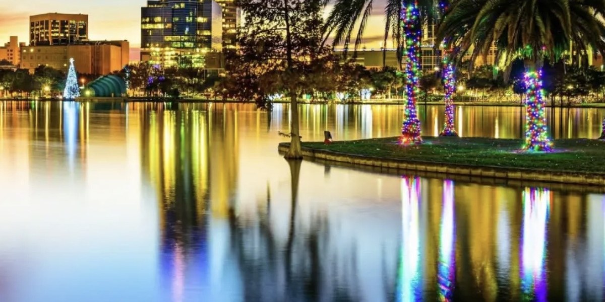 Lake Eola in Orlando at dusk, with a Christmas tree and palm trees wrapped in coloured lights reflected in the water